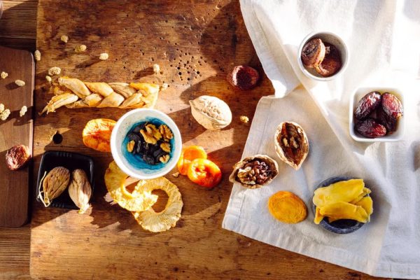 Top view of a rustic assortment of dried fruits and nuts on a wooden board, perfect for healthy snacks.