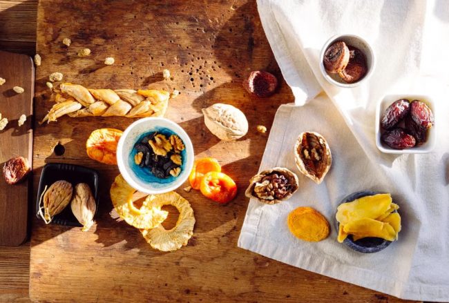 Top view of a rustic assortment of dried fruits and nuts on a wooden board, perfect for healthy snacks.