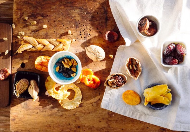 Top view of a rustic assortment of dried fruits and nuts on a wooden board, perfect for healthy snacks.