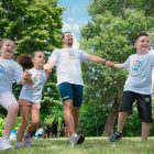 Group of joyful children playing outdoors with an instructor in a sunny park.