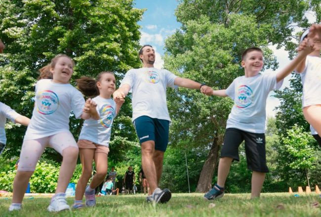 Group of joyful children playing outdoors with an instructor in a sunny park.